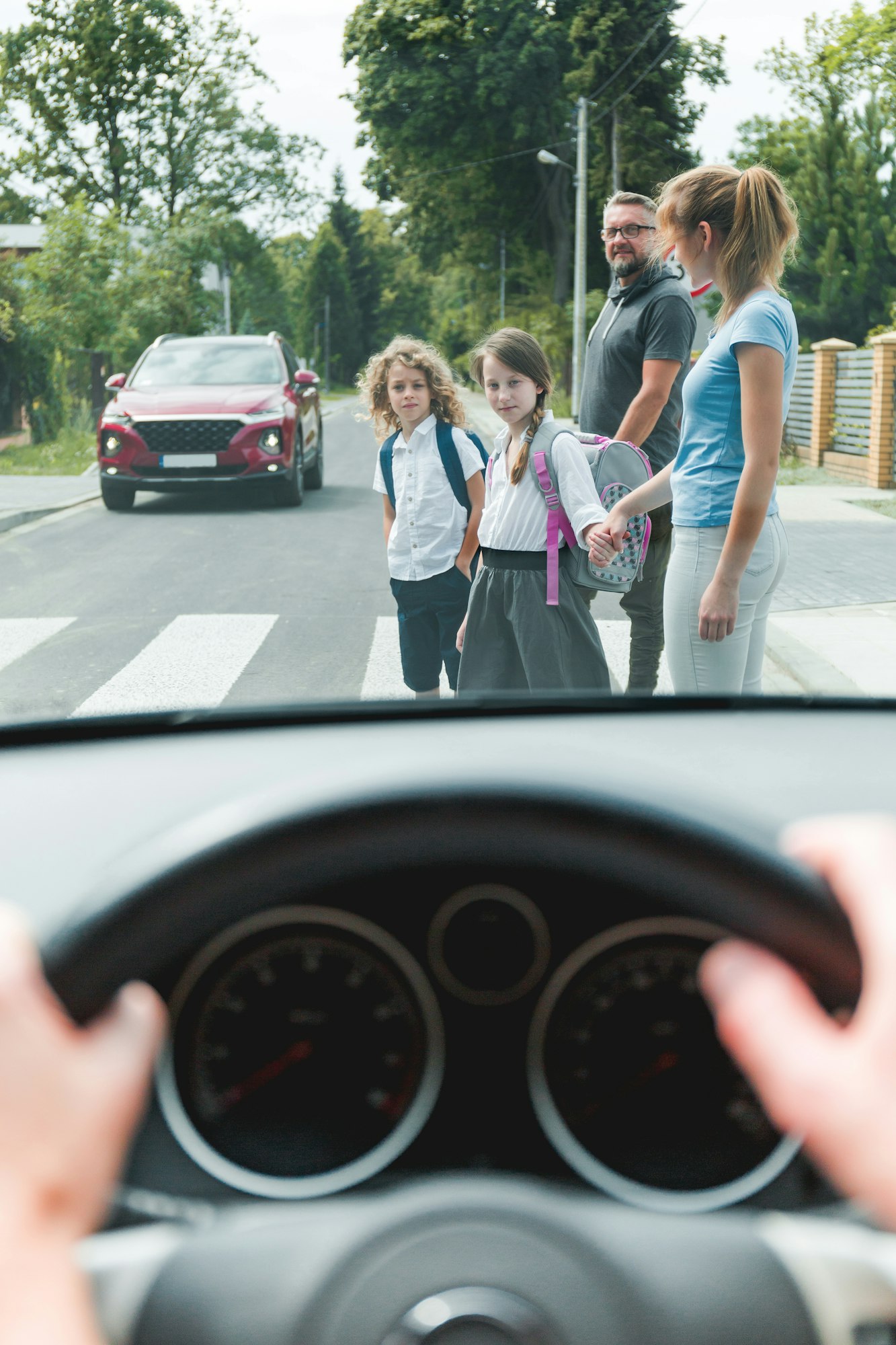Drivers point of view of family with children crossing a street on pedestrian area