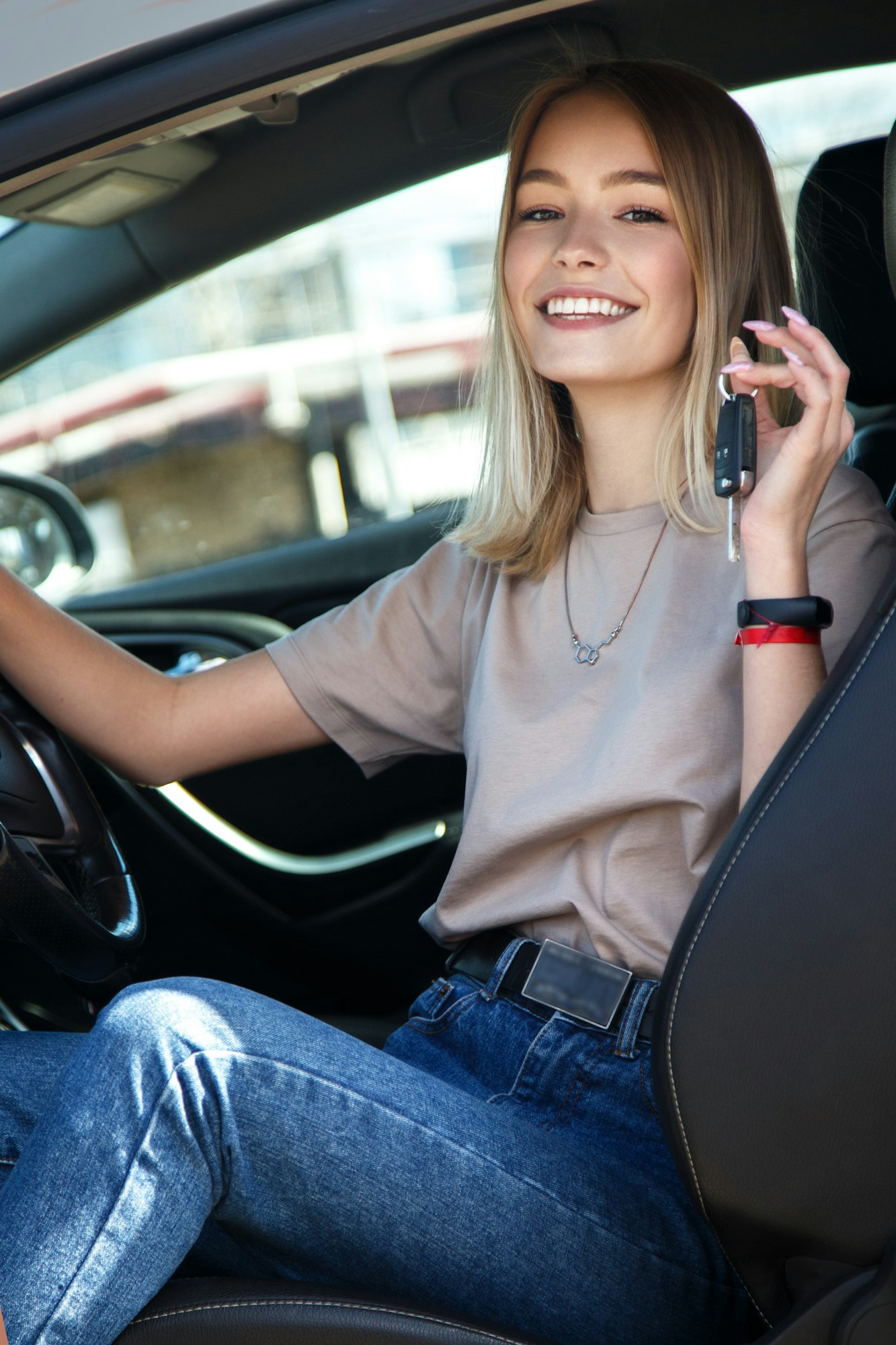 Happy smile girl in a new car with keys in her hand.